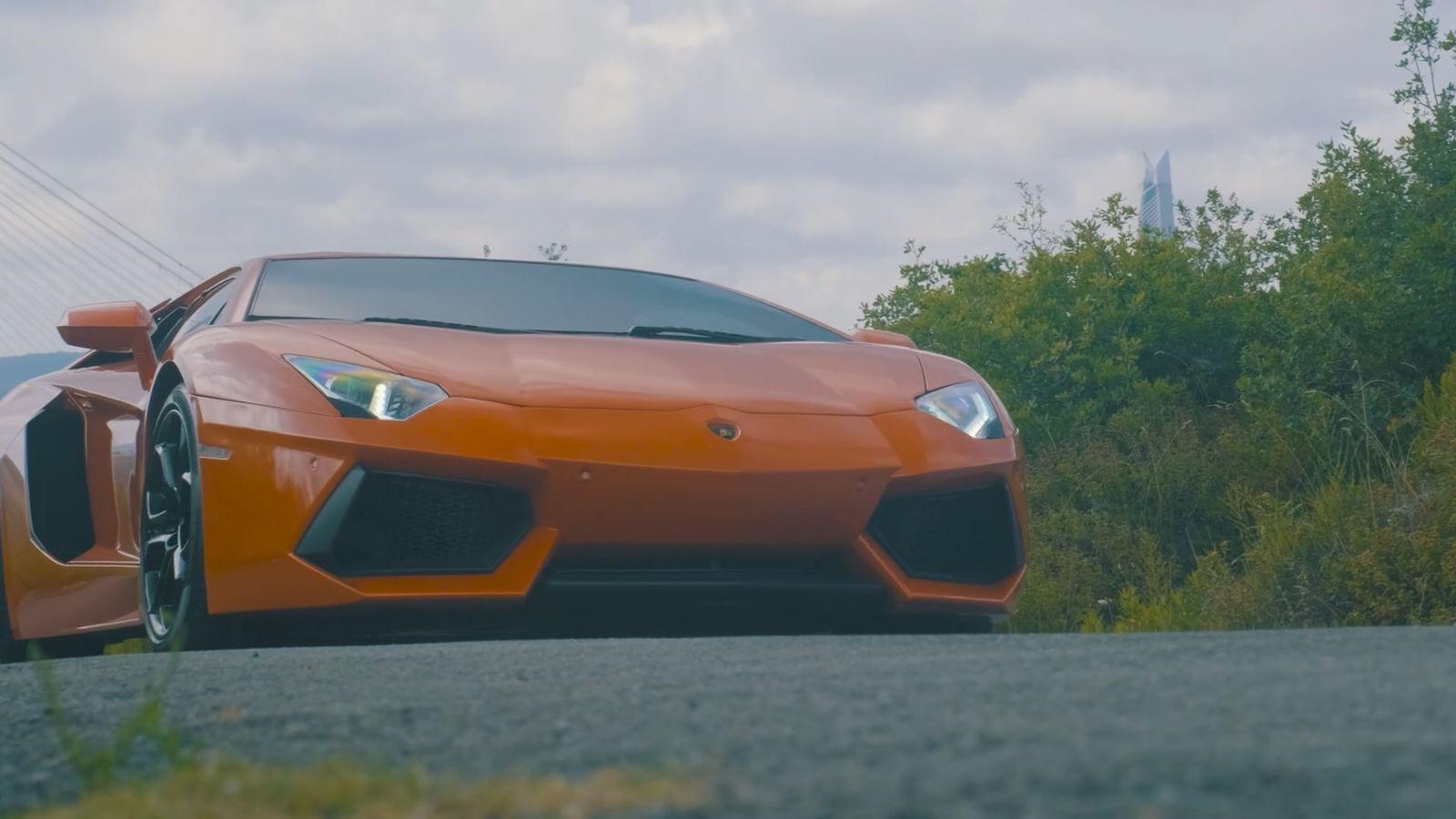 Orange sports car on a tree-lined road
